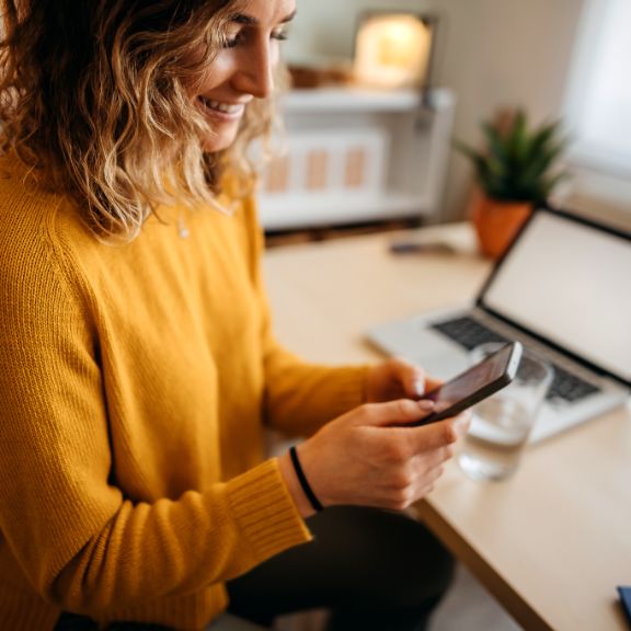 iStock-1348063575_Frau vor Handy und Notebook_enigma_images